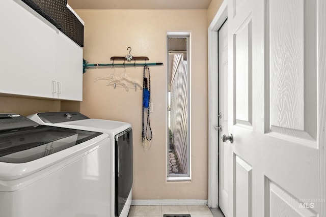 laundry area featuring cabinet space, washing machine and clothes dryer, baseboards, and light tile patterned floors