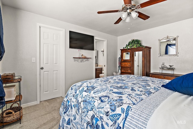 bedroom with light carpet, ensuite bathroom, baseboards, and ceiling fan