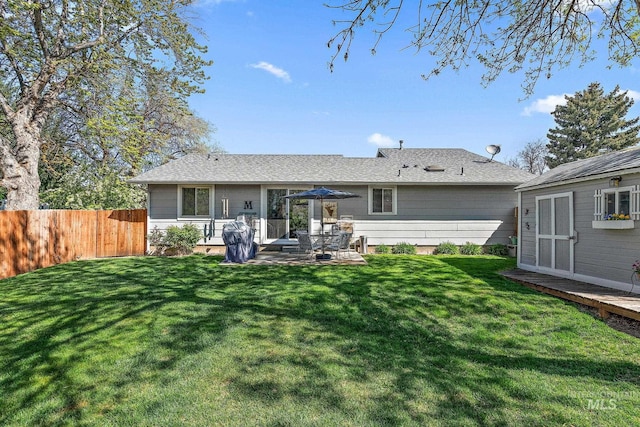 rear view of house with fence, a lawn, and a patio area