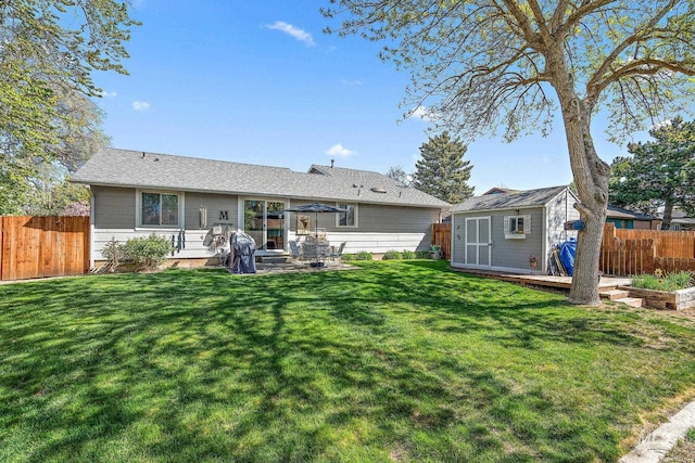 rear view of property featuring a storage shed, a lawn, a fenced backyard, an outbuilding, and a patio