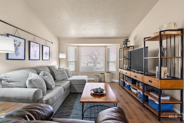 living room with lofted ceiling, baseboards, wood finished floors, and a textured ceiling