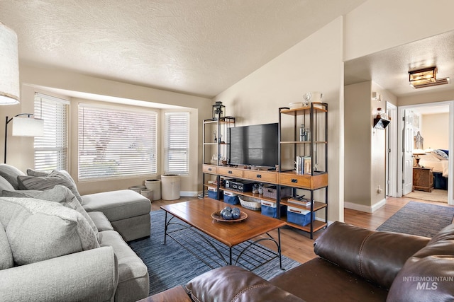 living area featuring vaulted ceiling, wood finished floors, a textured ceiling, and baseboards