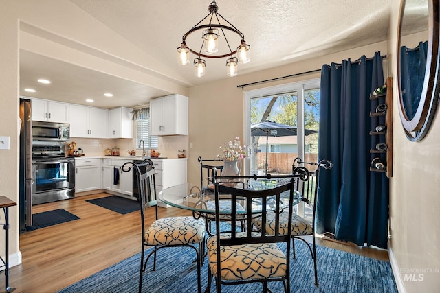 dining area featuring light wood finished floors, vaulted ceiling, and recessed lighting