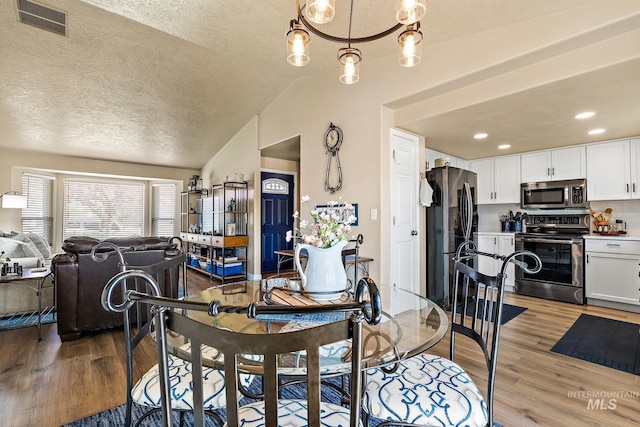 dining space featuring recessed lighting, vaulted ceiling, visible vents, light wood-style floors, and a textured ceiling