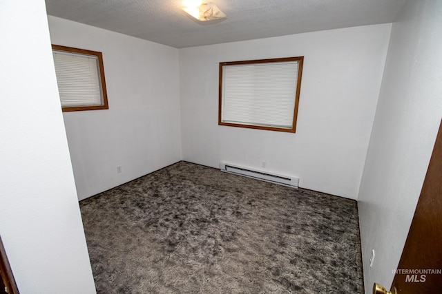 spare room with carpet floors, baseboard heating, and a textured ceiling