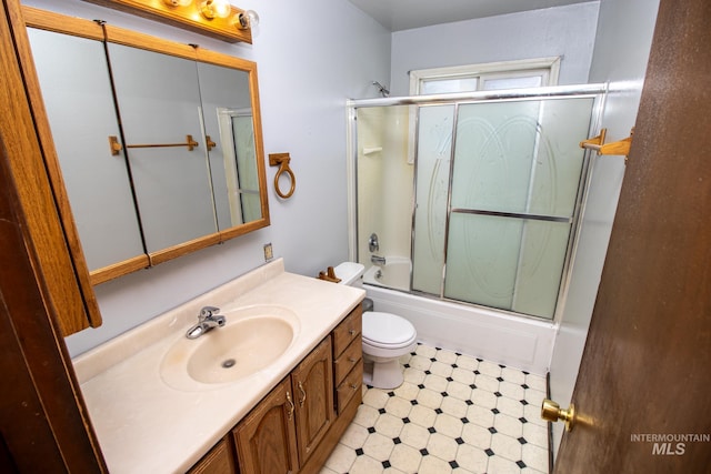 bathroom with tile patterned floors, toilet, vanity, and shower / bath combination with glass door