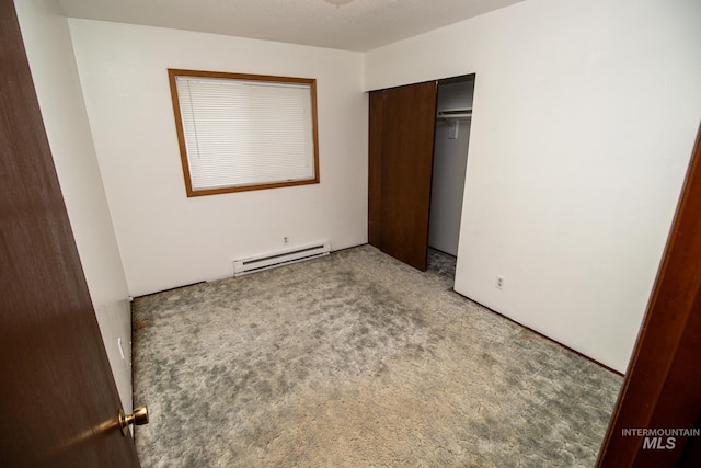 unfurnished bedroom with a closet, baseboard heating, and light colored carpet