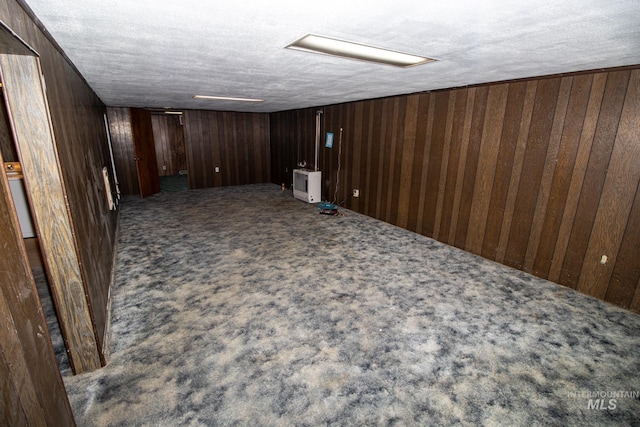 finished below grade area with carpet flooring, wood walls, and a textured ceiling