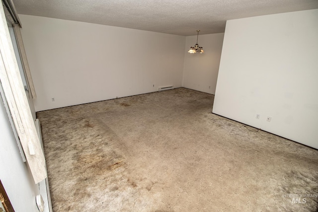 spare room featuring a textured ceiling, a baseboard heating unit, an inviting chandelier, and carpet floors