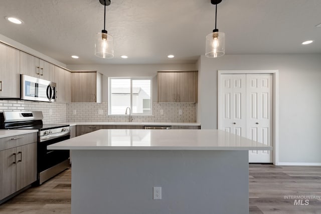 kitchen with stainless steel appliances, light wood-type flooring, light countertops, and a sink