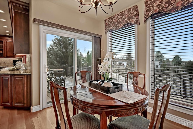 dining area with light wood-style floors, a notable chandelier, and baseboards