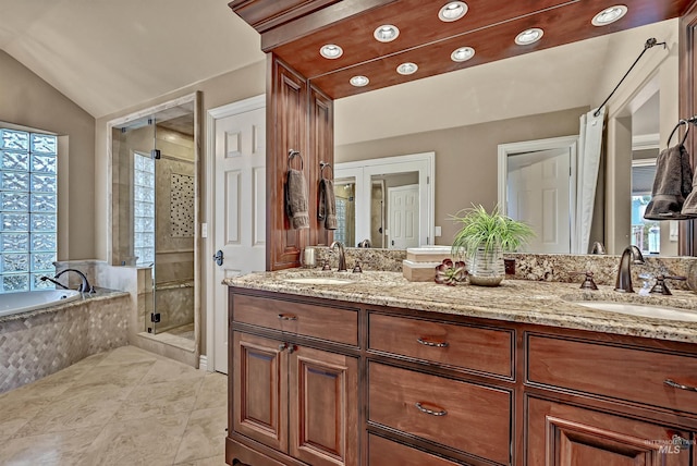 full bath with double vanity, a shower stall, vaulted ceiling, and a sink