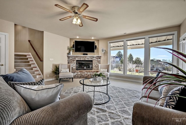 living area featuring ceiling fan, stairway, a fireplace, and carpet flooring