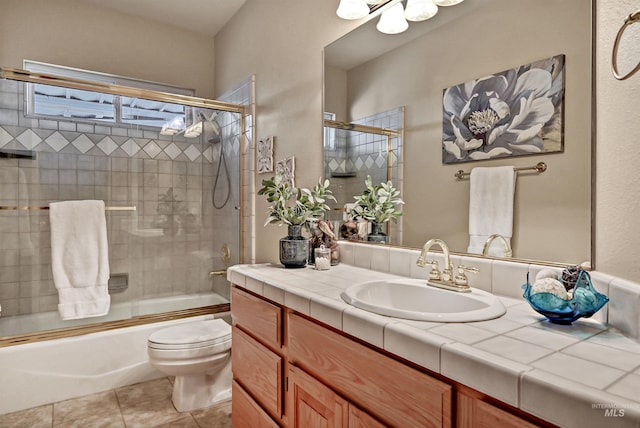 bathroom featuring tile patterned flooring, shower / bath combination with glass door, vanity, and toilet