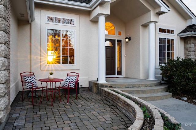 entrance to property featuring a patio area, visible vents, and stucco siding