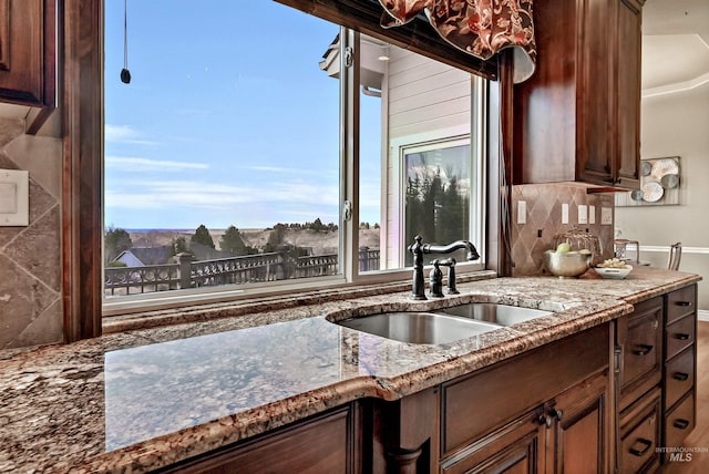 kitchen featuring stone counters, a sink, and backsplash