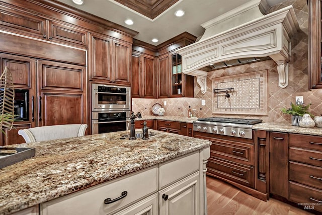 kitchen featuring tasteful backsplash, light wood-style flooring, glass insert cabinets, light stone counters, and stainless steel appliances