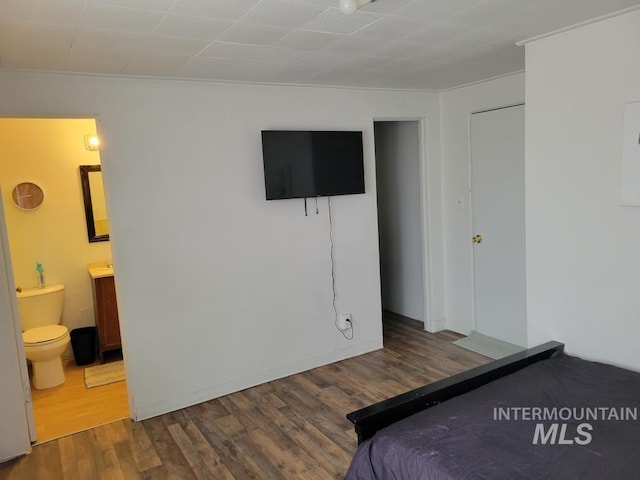 unfurnished bedroom featuring ensuite bathroom and dark hardwood / wood-style flooring