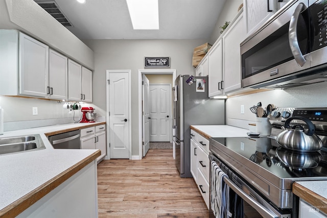 8116 Waterleaf Ave, Nampa, ID 83687 - kitchen featuring appliances with stainless steel finishes, a skylight, light wood-style floors, and white cabinetry