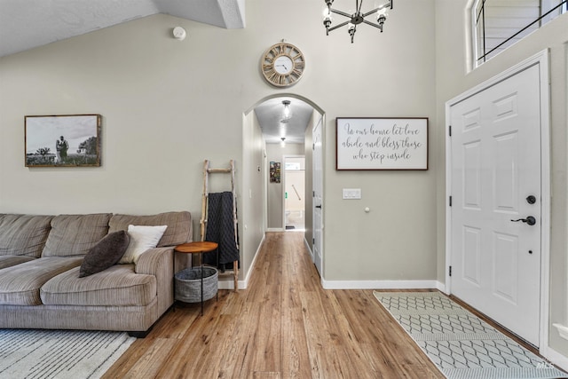 8116 Waterleaf Ave, Nampa, ID 83687 - foyer featuring light wood-style floors, arched walkways, baseboards, high vaulted ceiling, and a chandelier