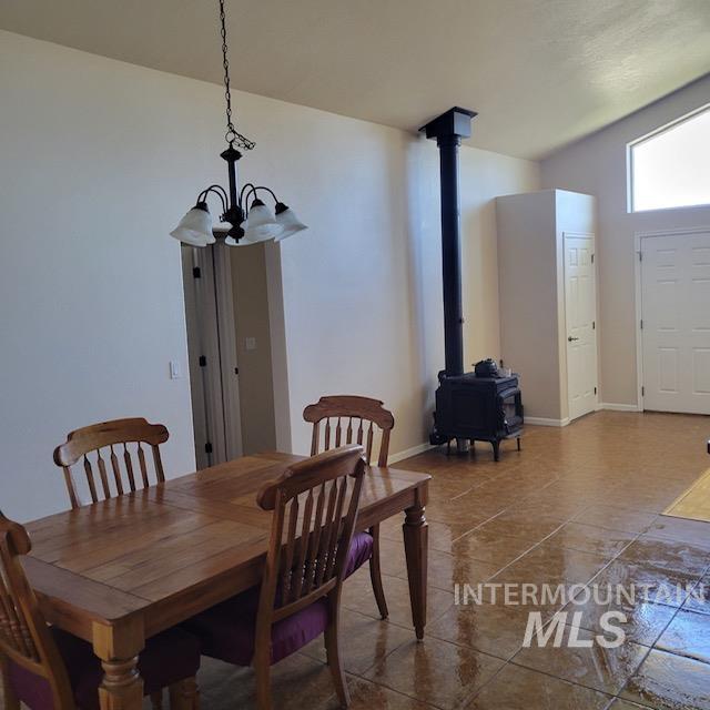 dining room with a wood stove, vaulted ceiling, and a notable chandelier