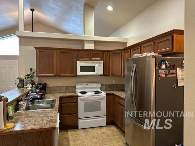 kitchen featuring white appliances, sink, and high vaulted ceiling