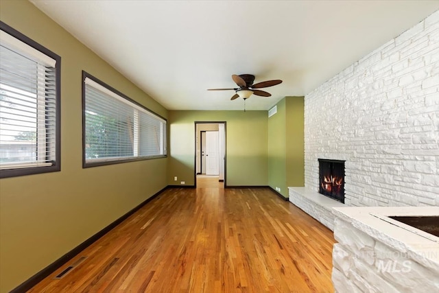 6917 W Randolph Dr, Boise, ID 83709 - unfurnished living room with a ceiling fan, wood finished floors, a stone fireplace, and baseboards