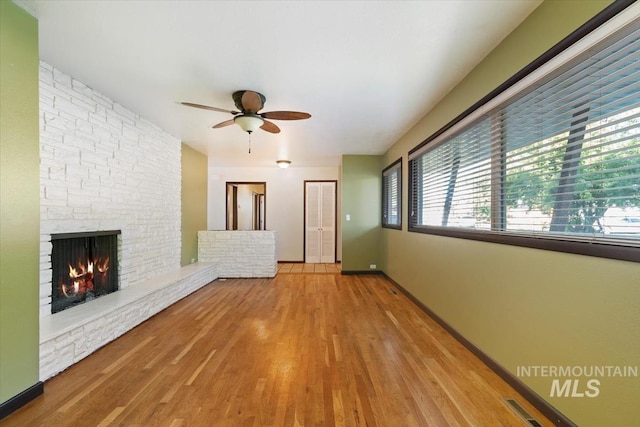 6917 W Randolph Dr, Boise, ID 83709 - unfurnished living room featuring a ceiling fan, a stone fireplace, wood finished floors, and baseboards