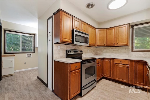 6917 W Randolph Dr, Boise, ID 83709 - kitchen with appliances with stainless steel finishes, light countertops, brown cabinetry, and plenty of natural light
