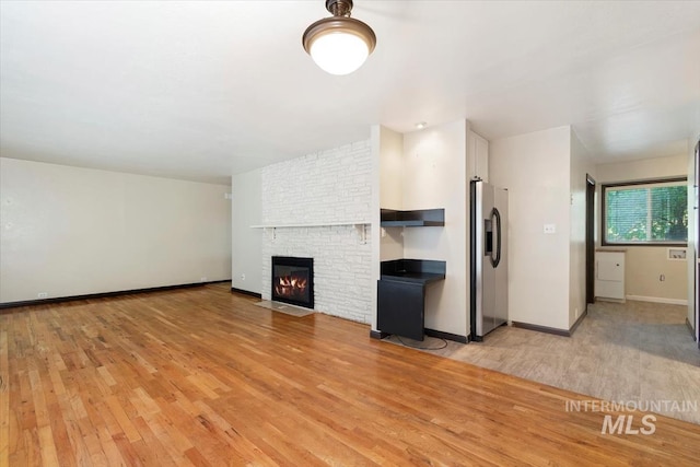 6917 W Randolph Dr, Boise, ID 83709 - unfurnished living room featuring light wood finished floors, a large fireplace, and baseboards