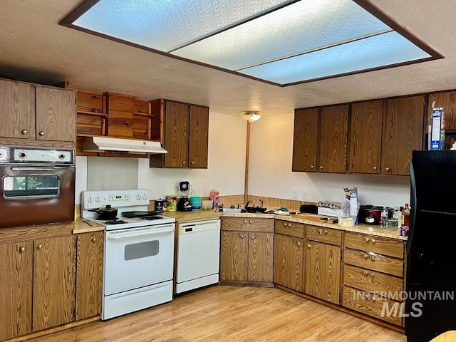 329 Forest St, Mccall, ID 83638 - kitchen with white appliances, under cabinet range hood, light countertops, a textured ceiling, and light wood-style flooring