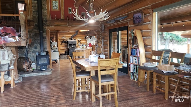 dining room featuring beam ceiling, a wood stove, rustic walls, wooden ceiling, and dark hardwood / wood-style floors