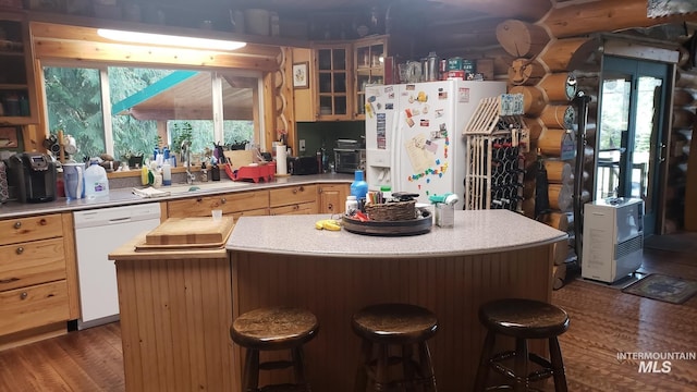 kitchen featuring a breakfast bar, a center island, white appliances, dark wood-type flooring, and sink