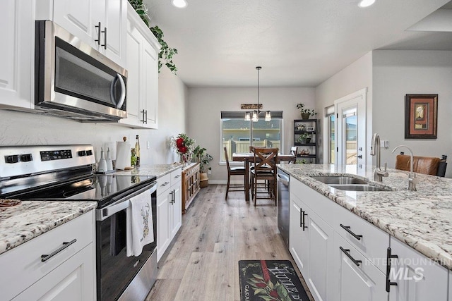 kitchen featuring sink, appliances with stainless steel finishes, plenty of natural light, white cabinets, and decorative light fixtures