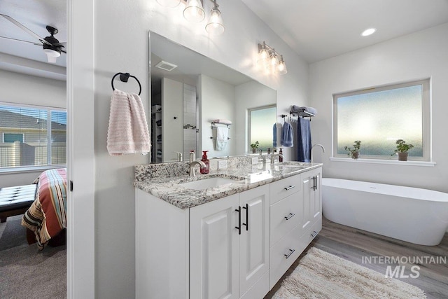 bathroom with ceiling fan, wood-type flooring, vanity, and a tub