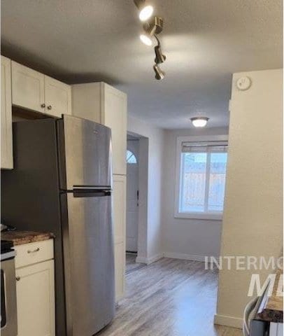3377 W Nez Perce St, Boise, ID 83705 - kitchen featuring dark countertops, freestanding refrigerator, light wood-type flooring, baseboards, and white cabinetry