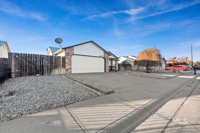 view of home's exterior featuring concrete driveway, brick siding, fence, and an attached garage