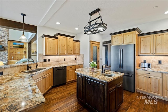 kitchen featuring a sink, dishwashing machine, light stone countertops, and stainless steel refrigerator