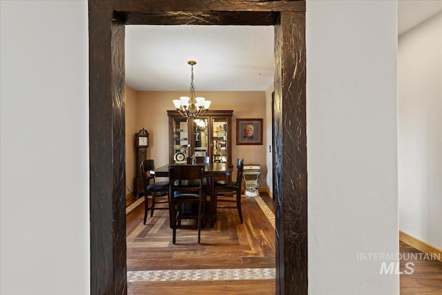 dining room with baseboards, wood finished floors, and a notable chandelier