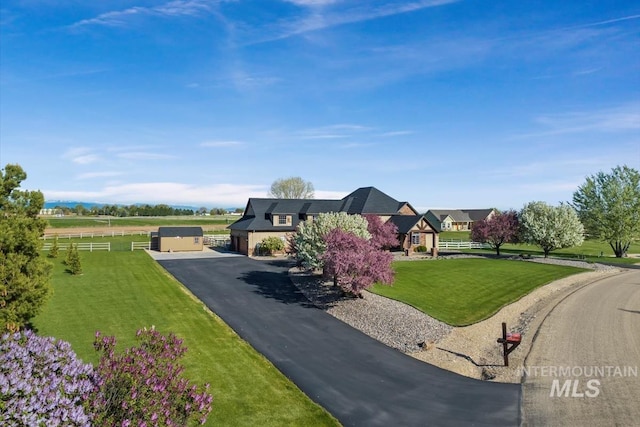 view of front of house featuring fence, aphalt driveway, and a front lawn