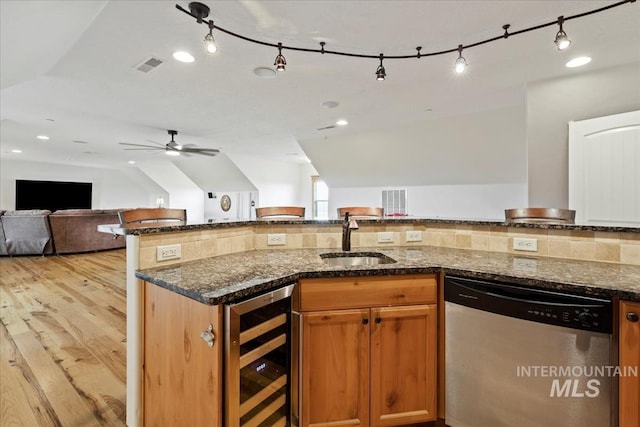 kitchen with a sink, dark stone countertops, open floor plan, wine cooler, and stainless steel dishwasher