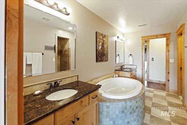 bathroom featuring visible vents, a sink, a garden tub, and two vanities