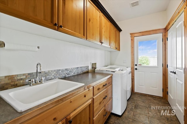 laundry area featuring stone finish floor, independent washer and dryer, visible vents, cabinet space, and a sink