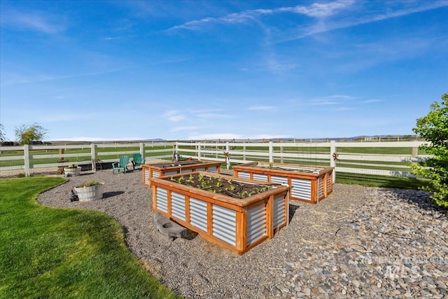 view of yard with a rural view, fence, and a vegetable garden
