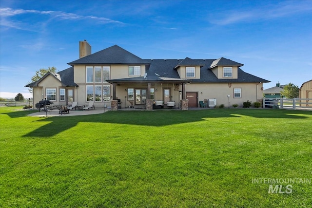rear view of property with a lawn, fence, a chimney, and stucco siding