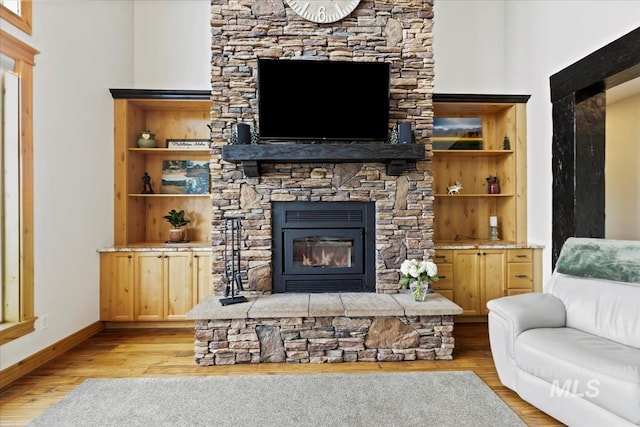 living area featuring baseboards, a fireplace, and light wood finished floors
