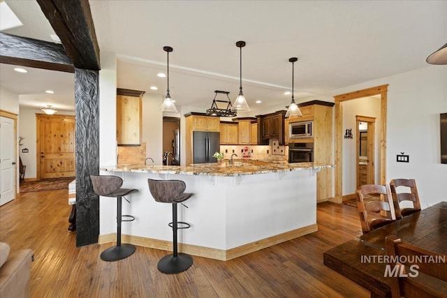 kitchen with freestanding refrigerator, wall oven, stainless steel microwave, and a breakfast bar area