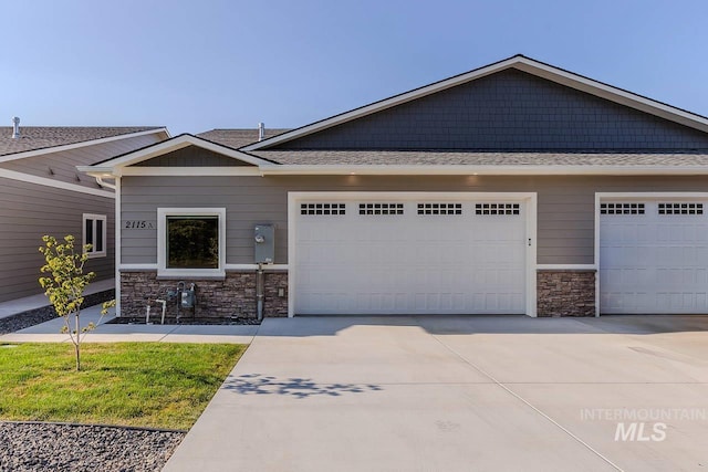 view of front of home with an attached garage, stone siding, and concrete driveway