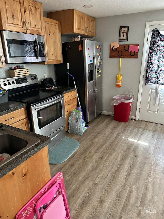 kitchen featuring stainless steel appliances, light hardwood / wood-style flooring, and a textured ceiling