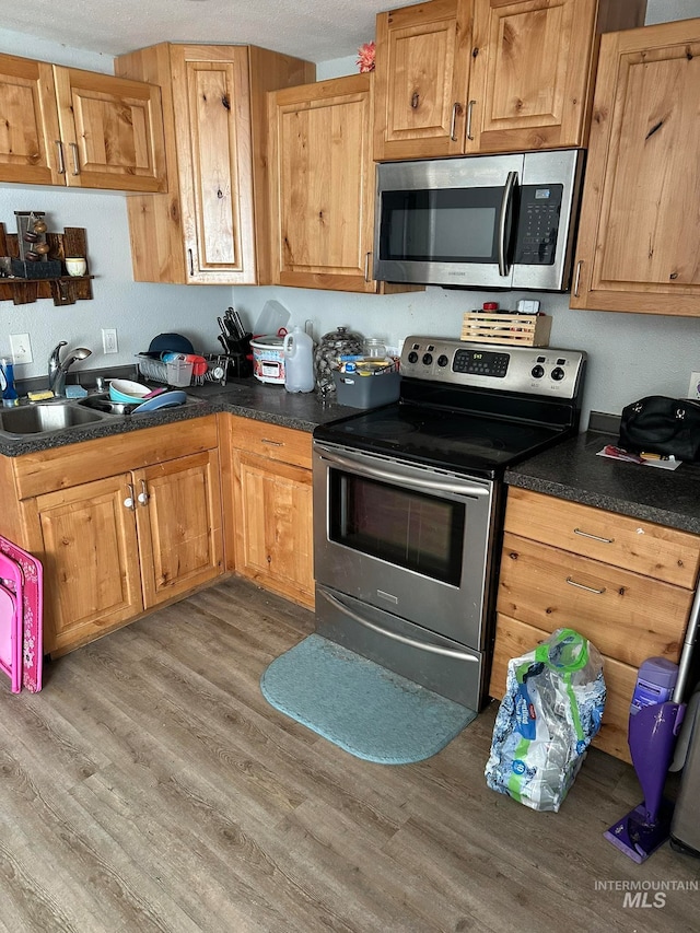 kitchen featuring appliances with stainless steel finishes, sink, and hardwood / wood-style floors